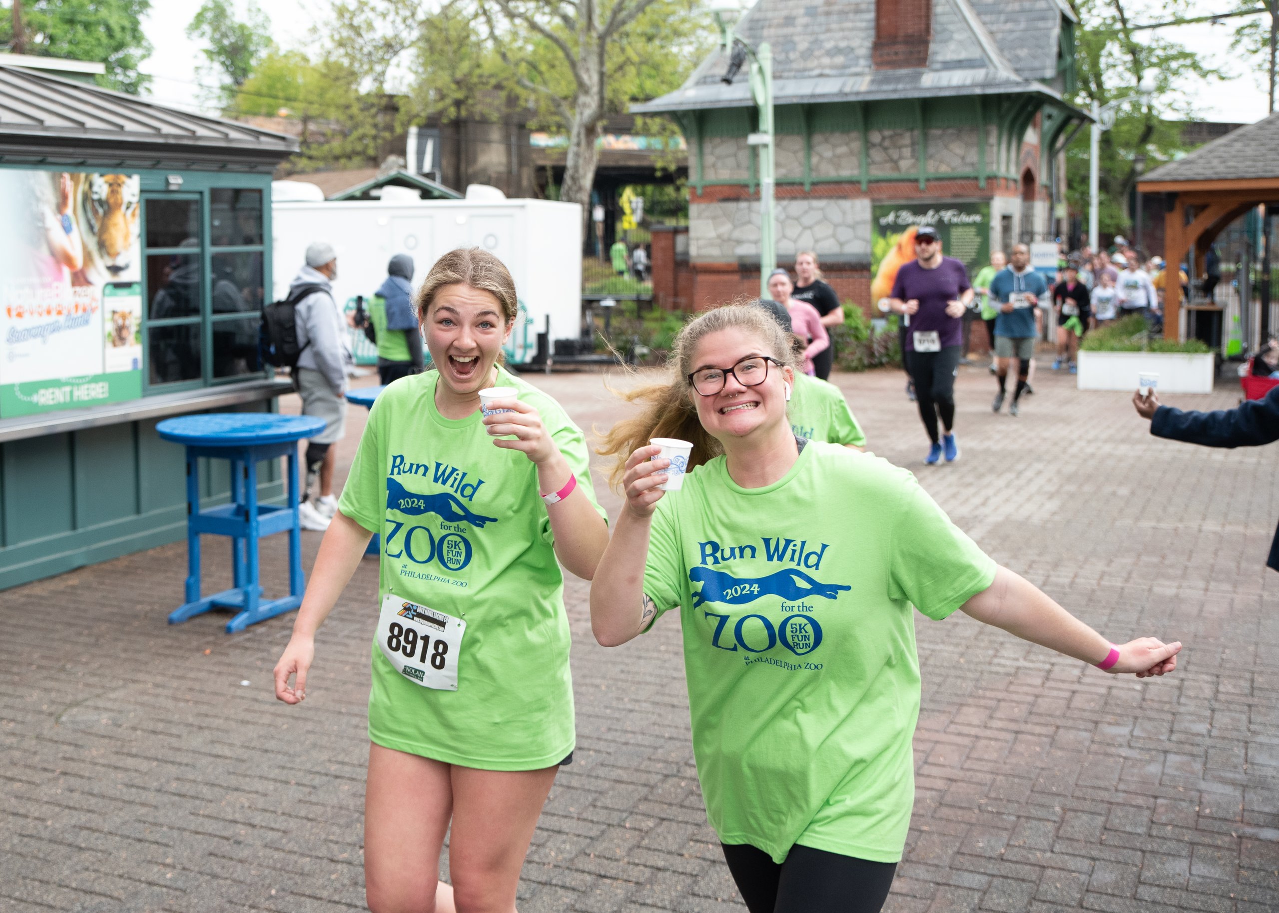 Two runners smile while passing through the main gate at the Philadelphia Zoo Run Wild 5K and Fun Run Event.