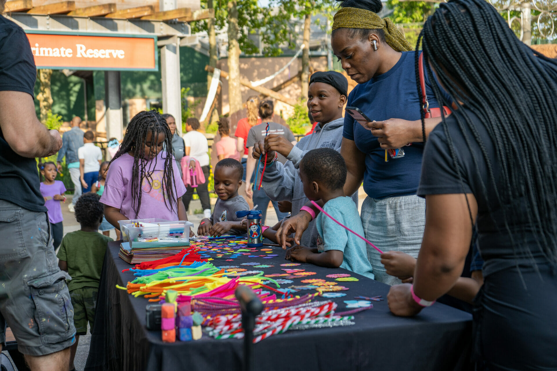 A group of parents and children gather around an arts and crafts table at Philadelphia Zoo's community night.