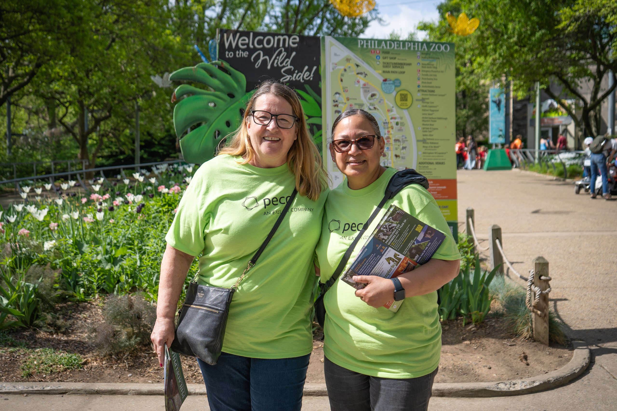 Two volunteers smile for a photo at the entrance gate of Philadelphia Zoo.
