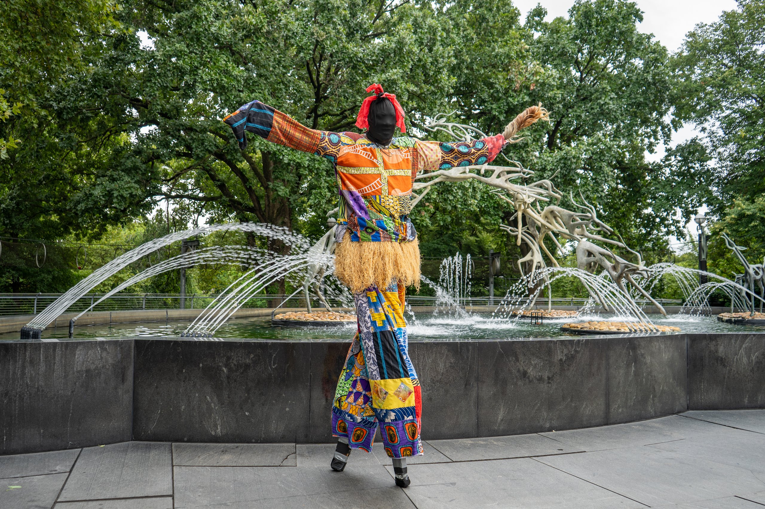 A stilt walker poses by Impala Fountain during African Culture Fest.