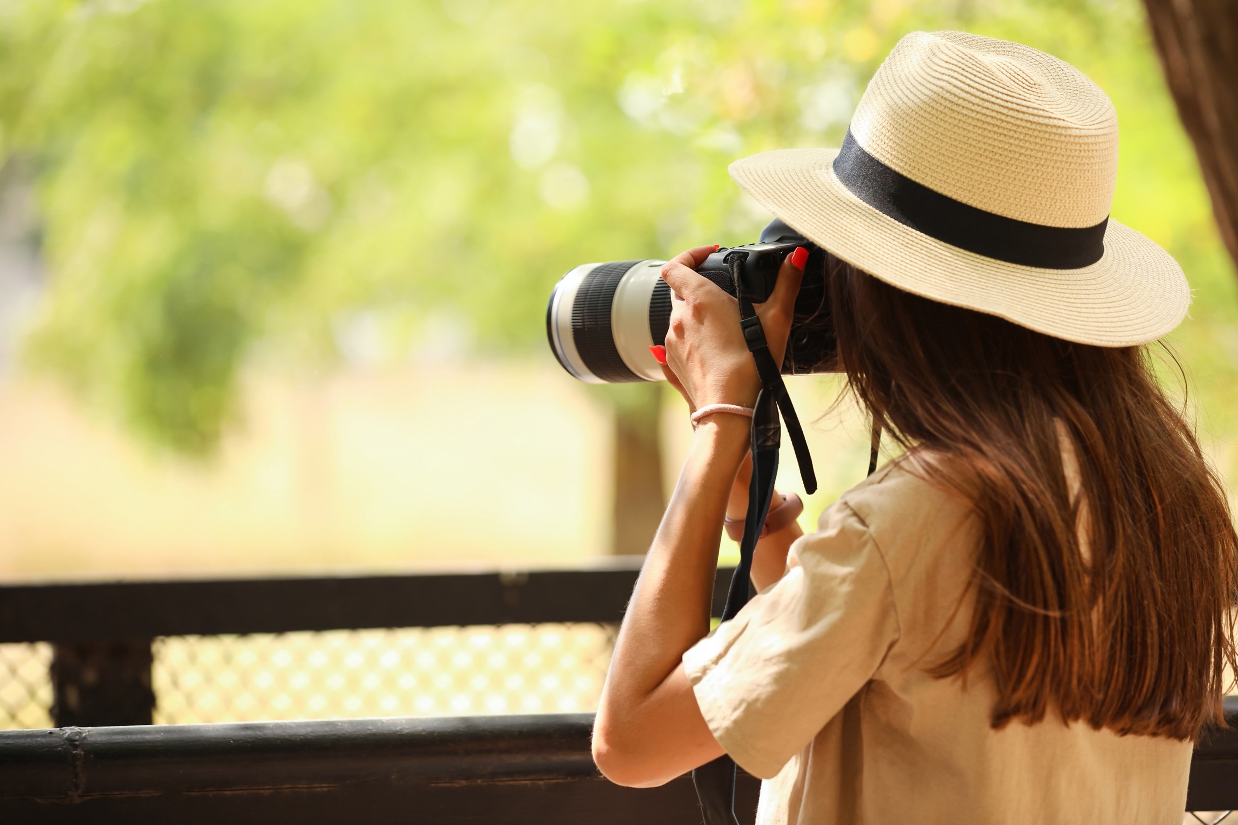 A photo of a woman looking through the viewfinder of a camera.