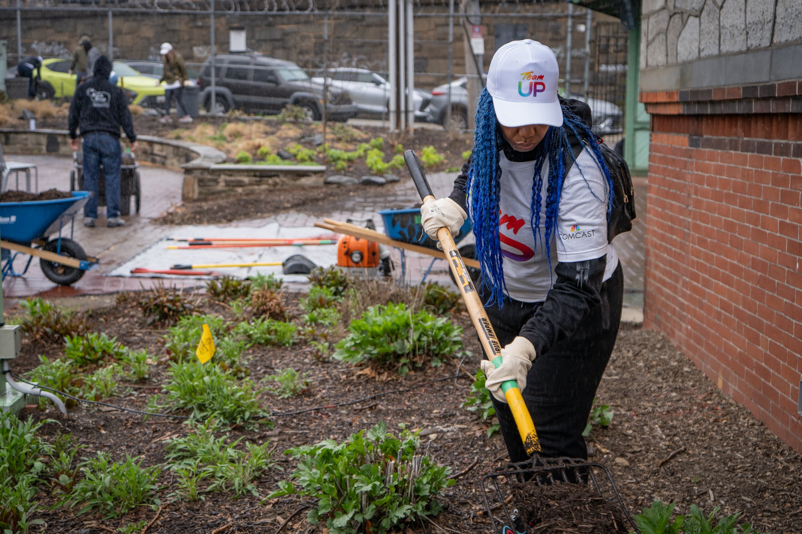 A volunteer tends to the gardens with a rake at Philadelphia Zoo.