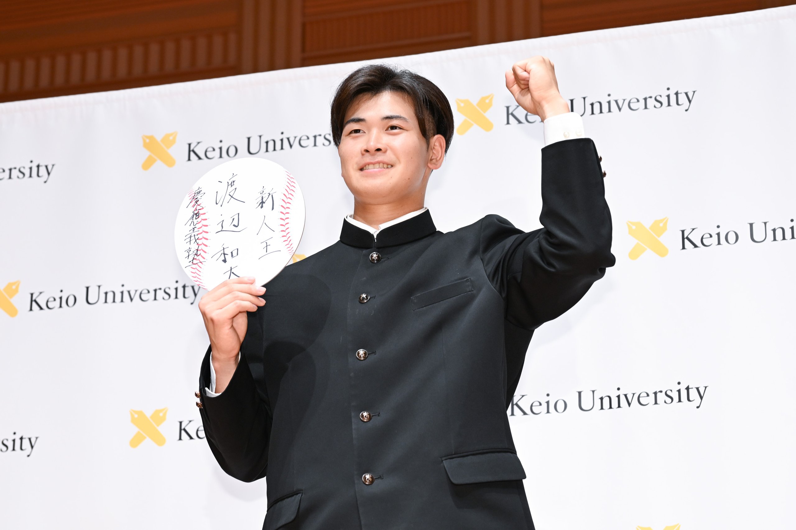 「新人王」と抱負を書いた色紙を手に、ガッツポーズをする渡辺君の写真