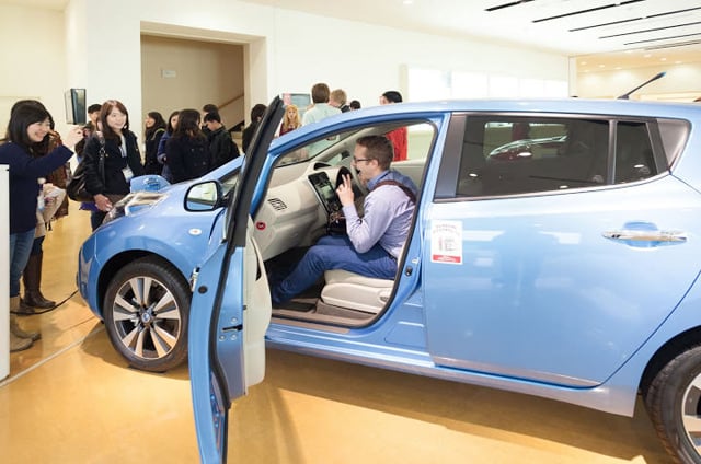 Students taking part in a hands-on learning experience with a displayed vehicle.