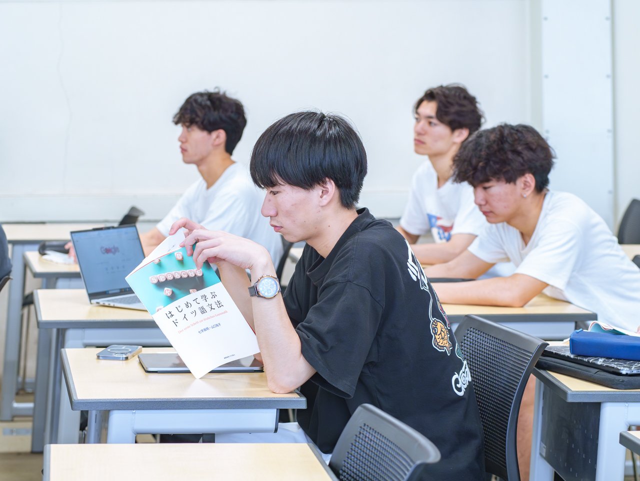 A photo of students studying with their textbooks open in a classroom.