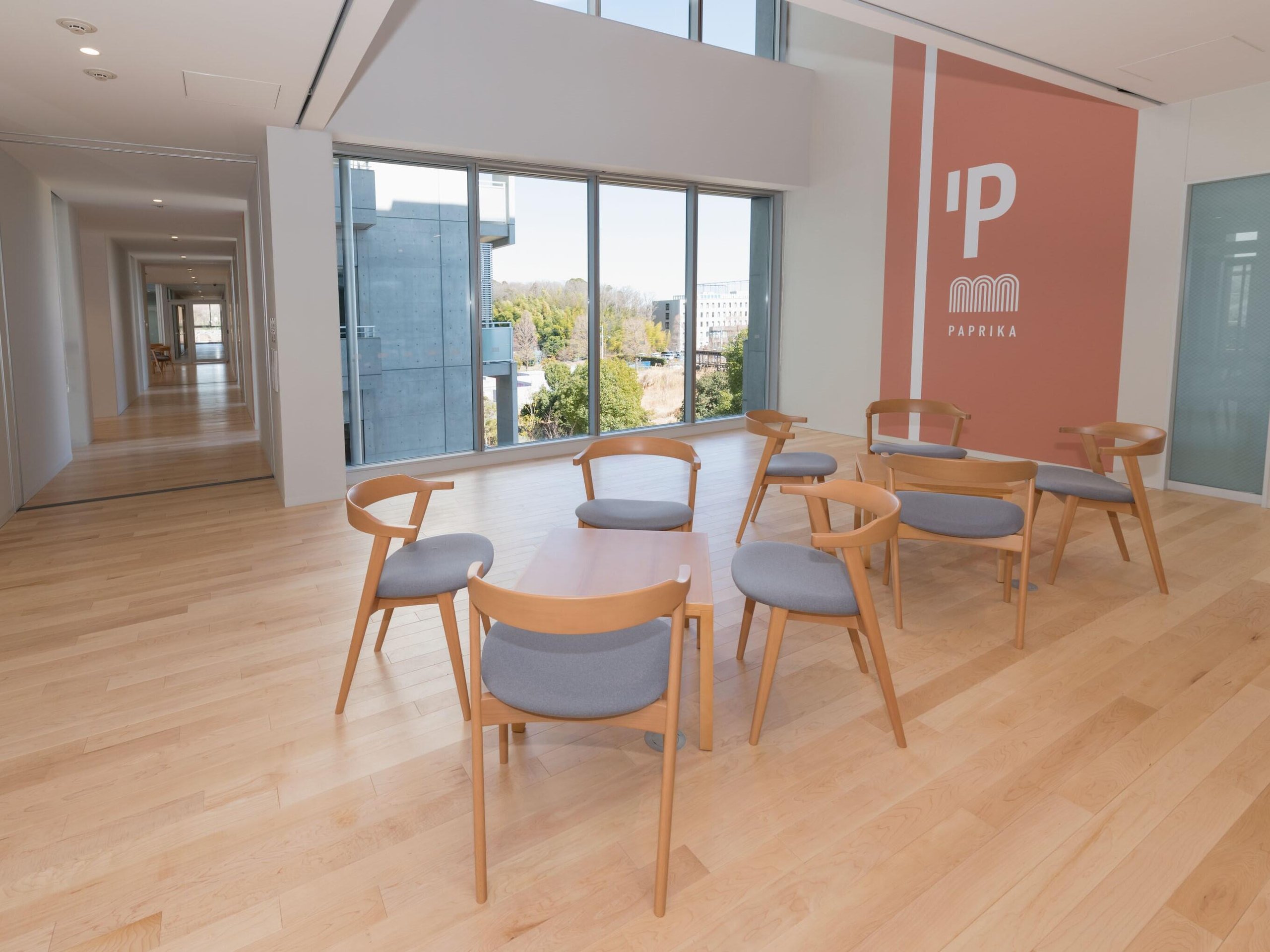 A bright indoor lounge area with wooden floors and a wall featuring the "PAPRIKA" logo.