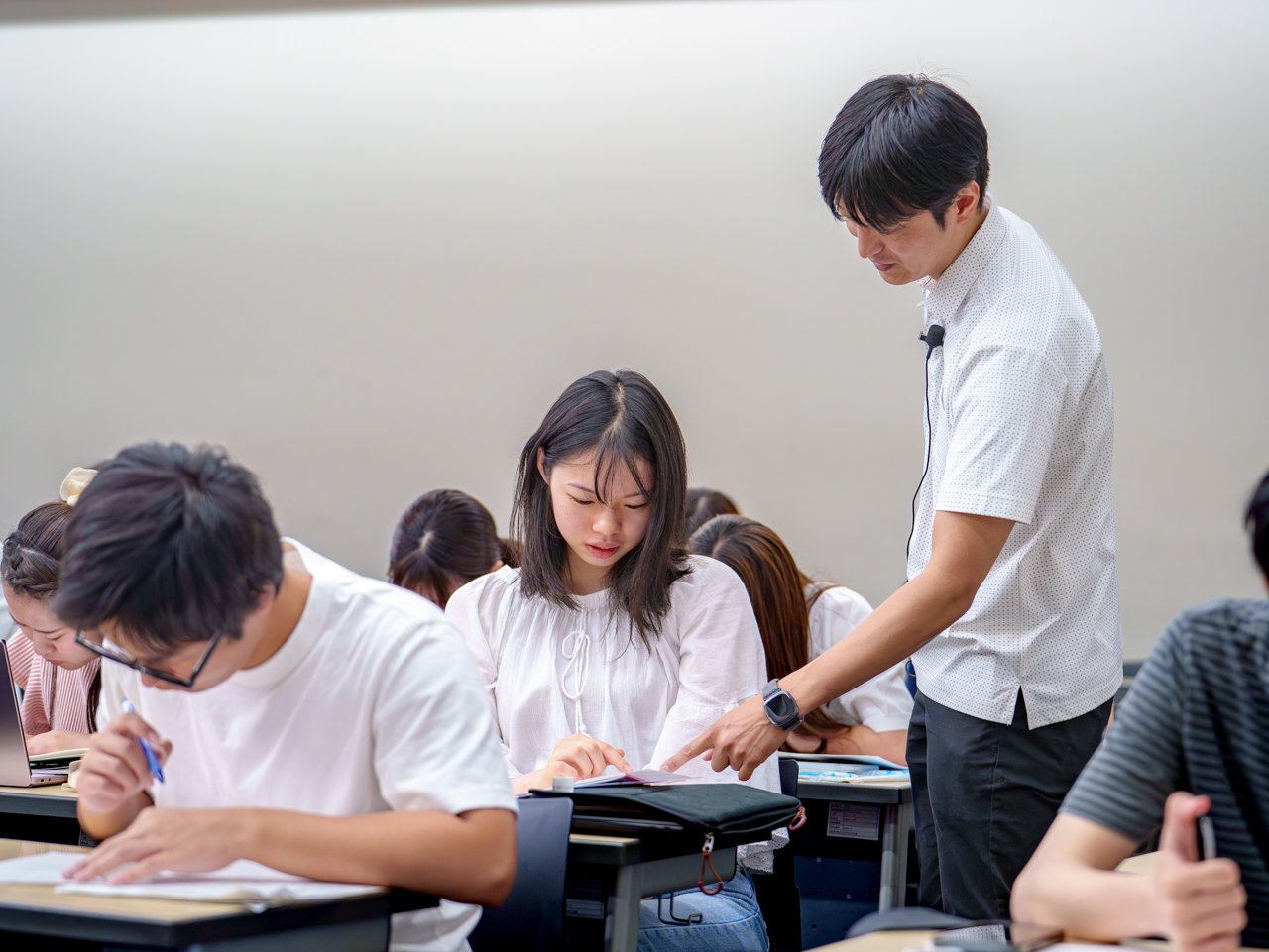 A photo of an instructor walking among students solving practice problems and answering their questions.