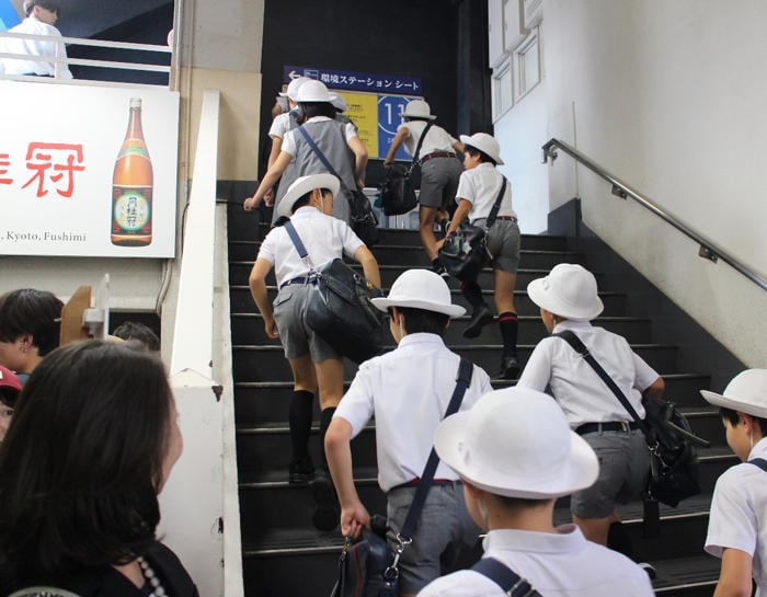 球場の階段を登り、スタンドへ向かう制服姿の学生たち。