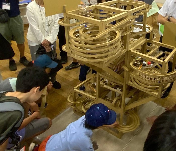Visitors watching the operation of a student work (marble coaster)