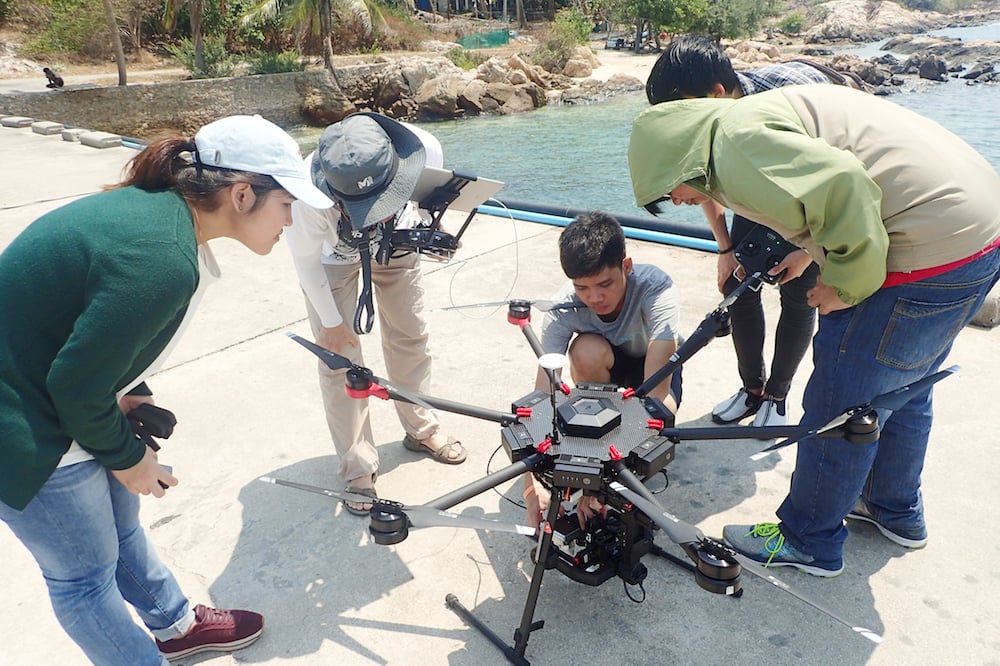 数名が機械のまわりを囲んでいる写真。