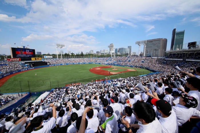 メガホンを手に、超満員のスタンドからグラウンドへ声援を送る学生たち。