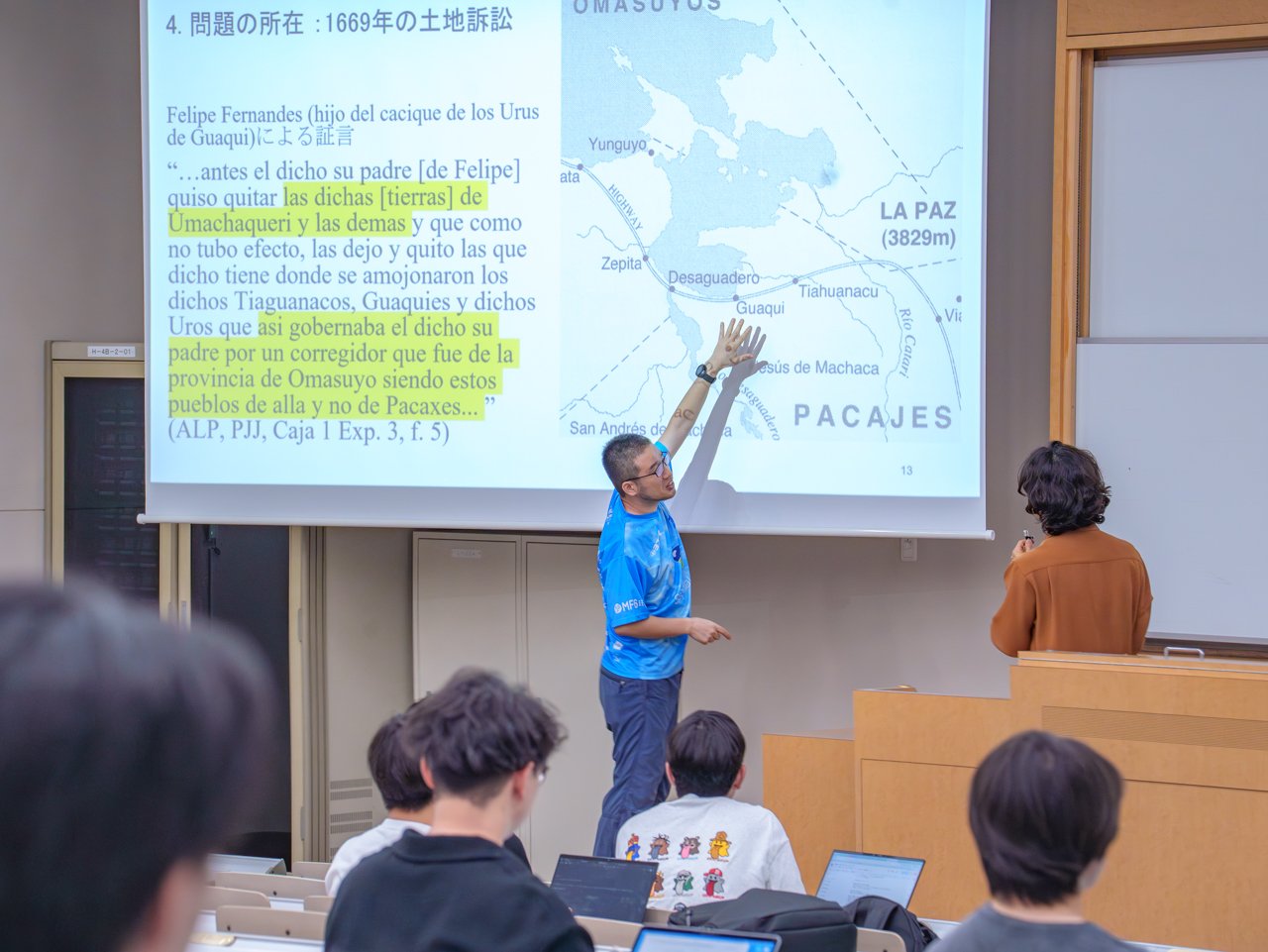 二人の教員がプロジェクターに映し出されたマップを前に、議論する様子