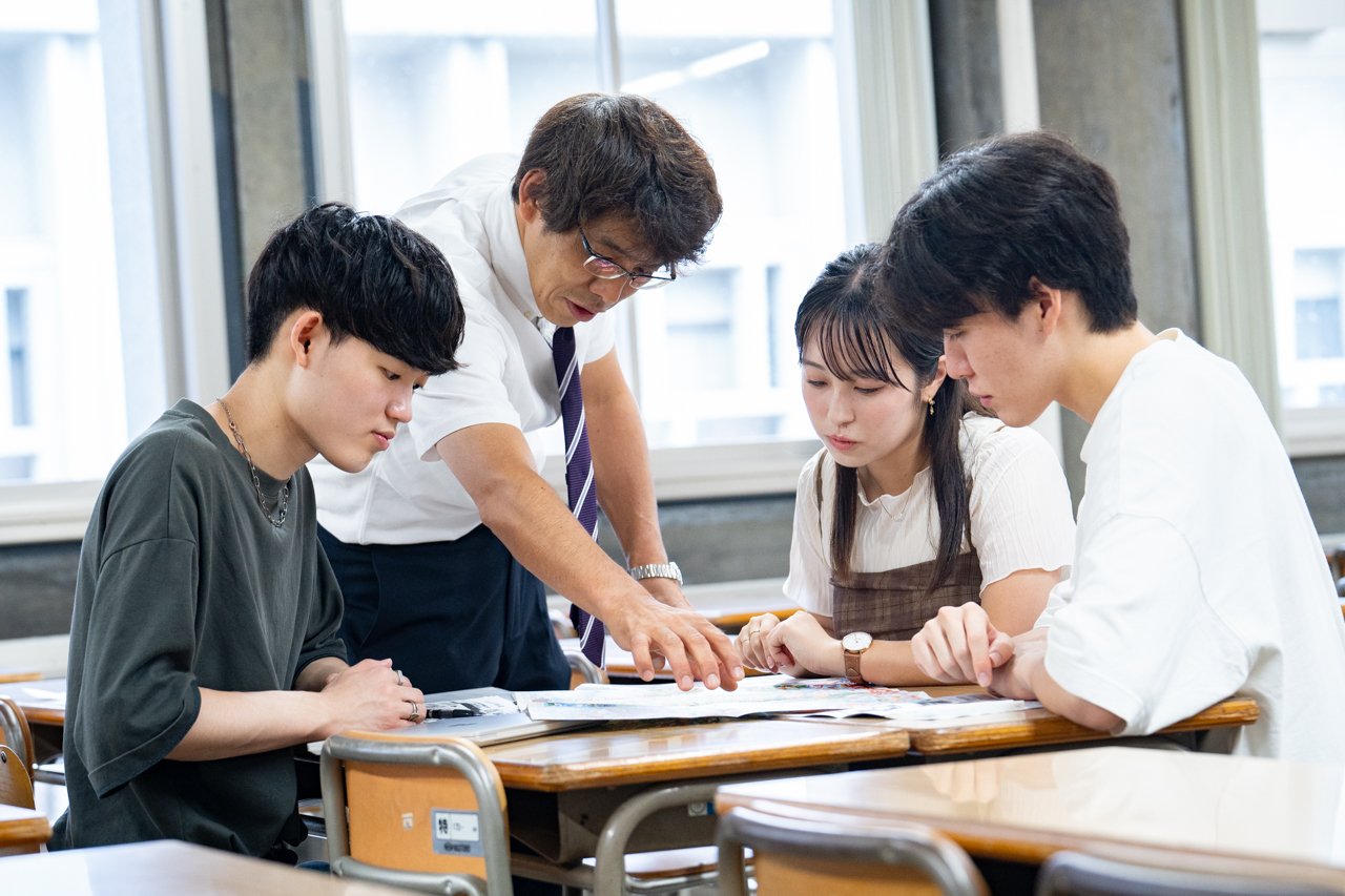 Photo of three students engaged in group work and a faculty member