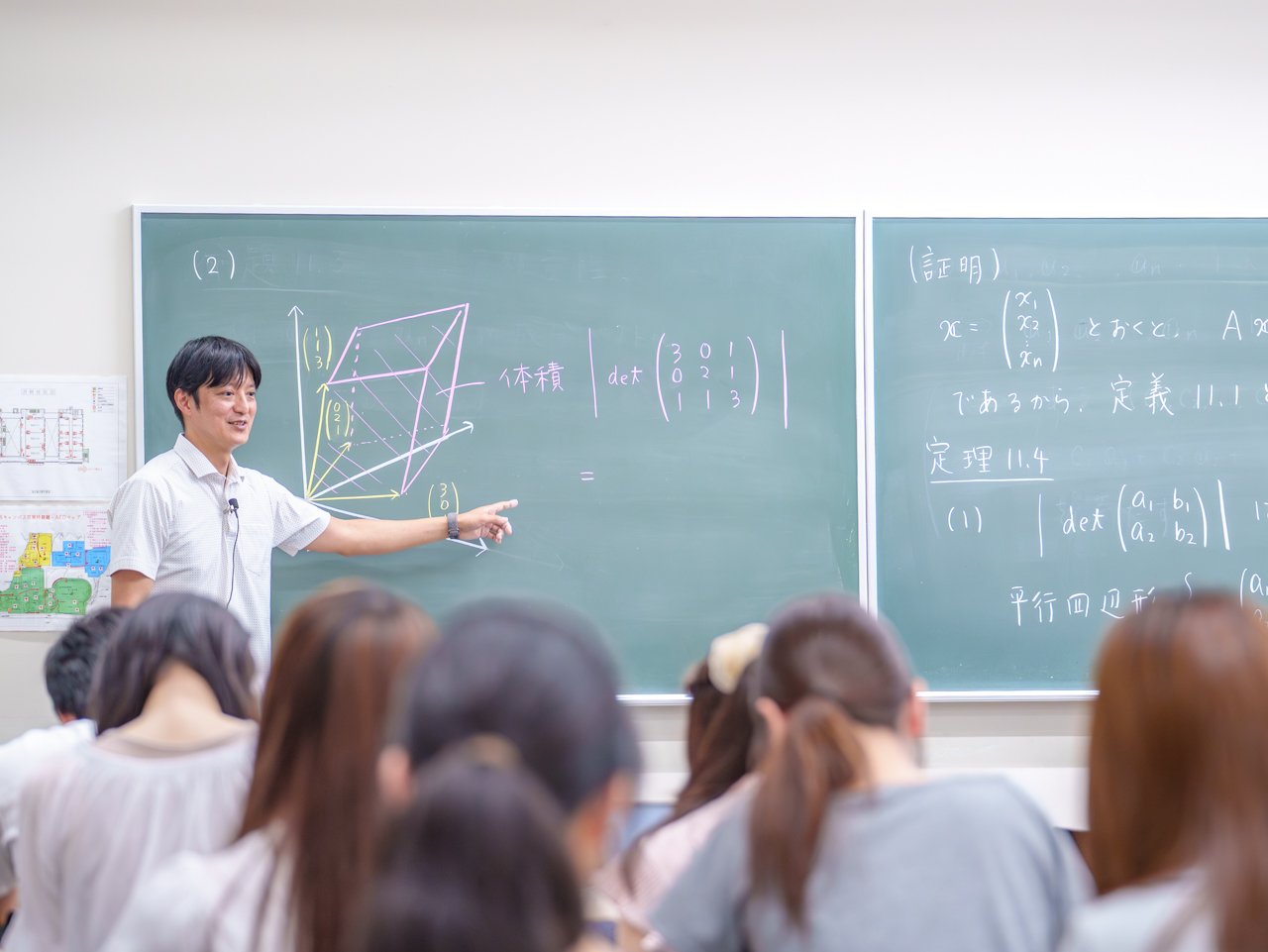 A photo of a teacher explaining while drawing a vector diagram on a blackboard.