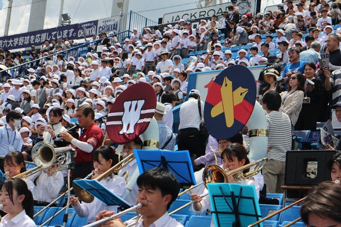 早慶両校のエンブレムを掲げて演奏する吹奏楽団。