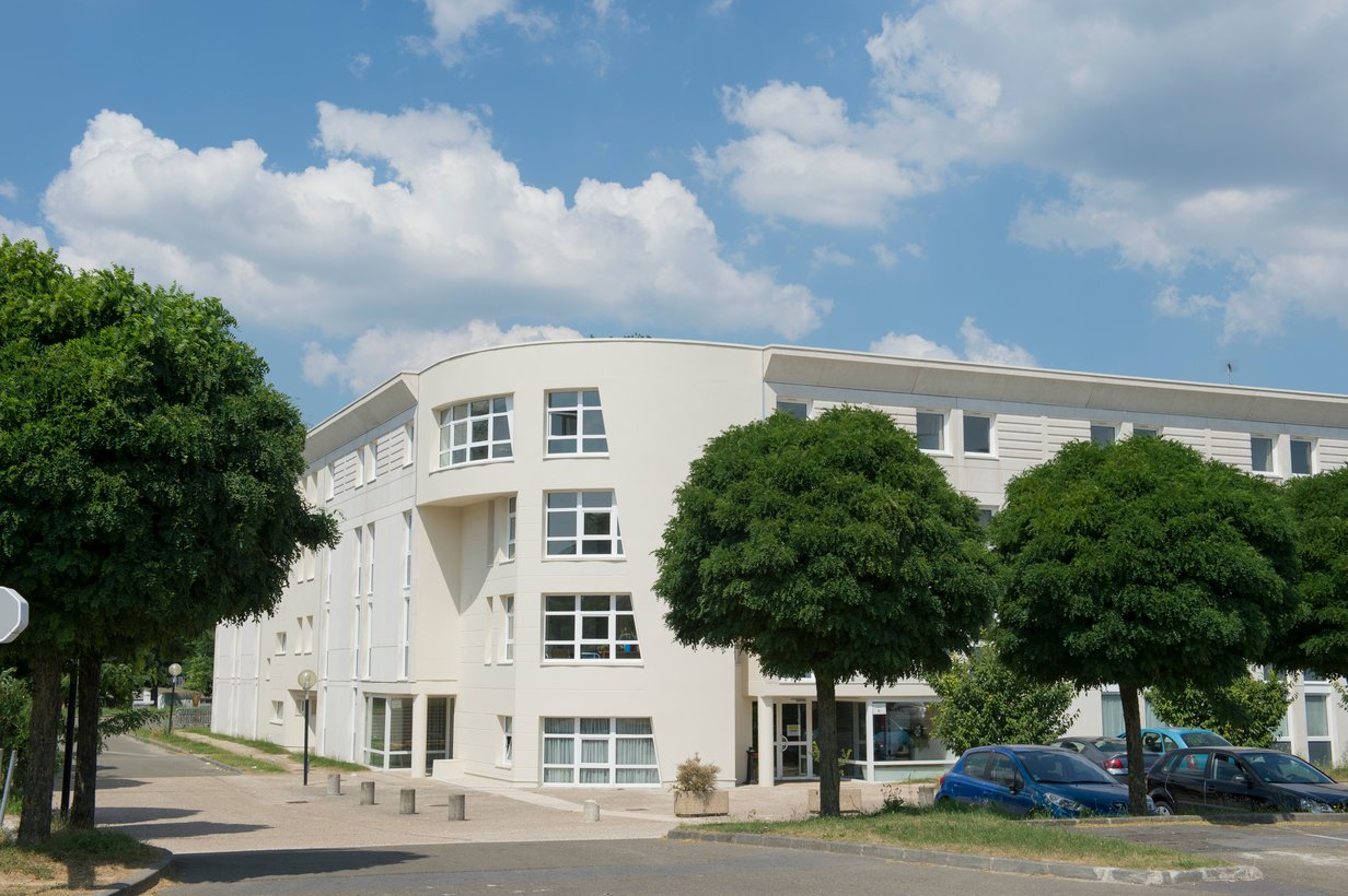 Exterior of HEC Paris. White buildings are surrounded by nature.