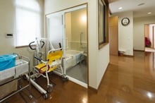 バリアフリー設計の浴室と、その横に設置された黄色いシャワーキャリー（入浴用車椅子）。