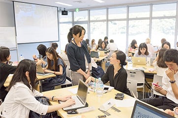 Students working on assignments while engaging in discussion with an instructor.