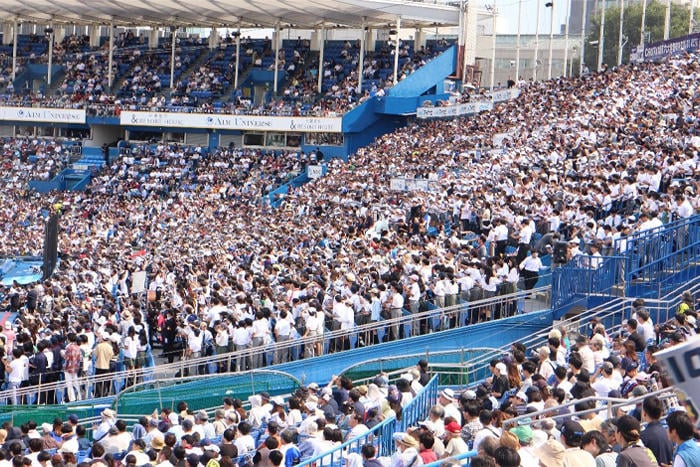 明治神宮野球場のスタンドを埋め尽くす、大勢の観客と学生たち。