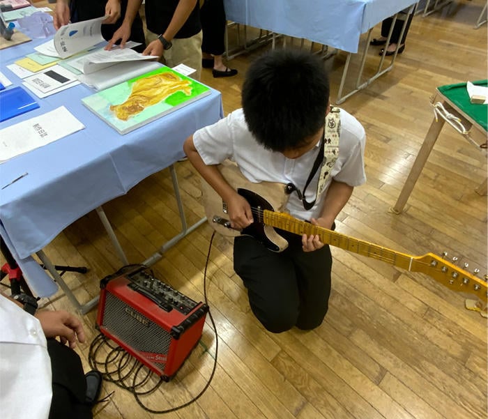A Futsubu student trying out a friend's work (electric guitar)