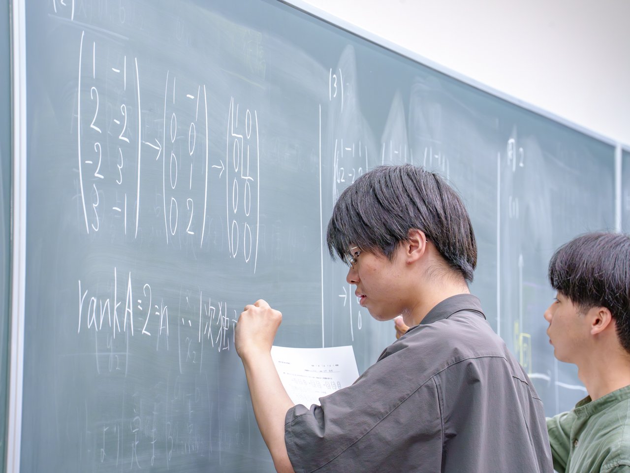 Students writing their solutions on the blackboard and presenting them.