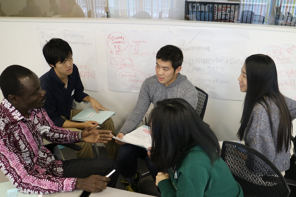 教室で5名の人物がディスカッションしている写真。