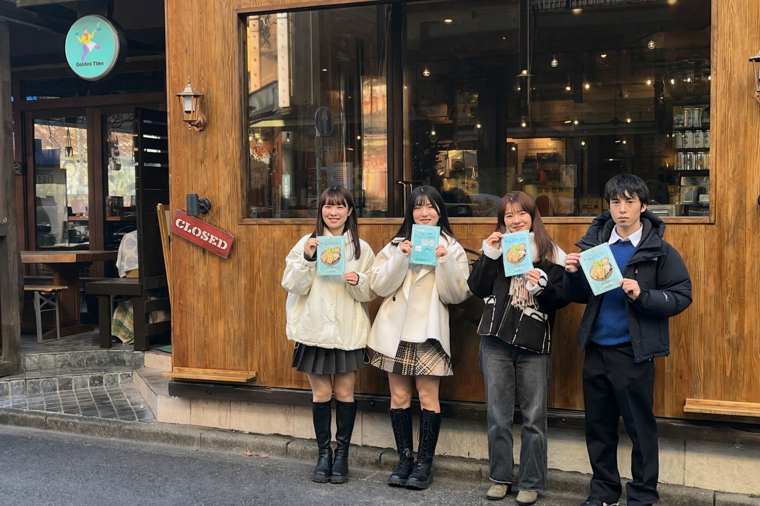 地域の飲食店にてキャンペーンに参加した学生たちが店舗前でほほ笑んでいる写真