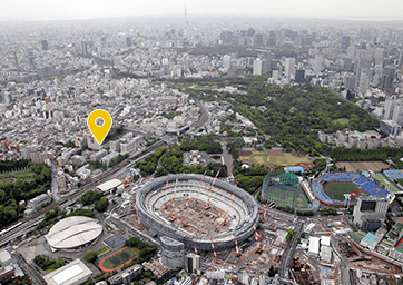 建設中の国立競技場とその周辺を捉えた空撮写真。左側の慶應義塾大学病院の位置に黄色いピンが立てられている。