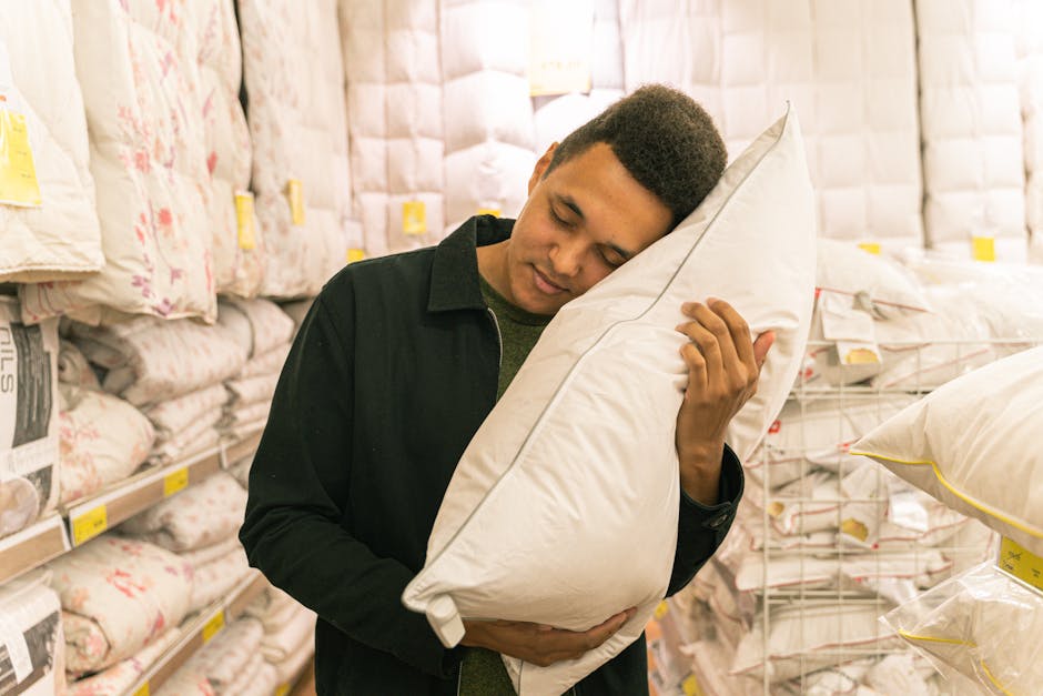 Man enjoying and testing a pillow in a bedding store, surrounded by merchandise.