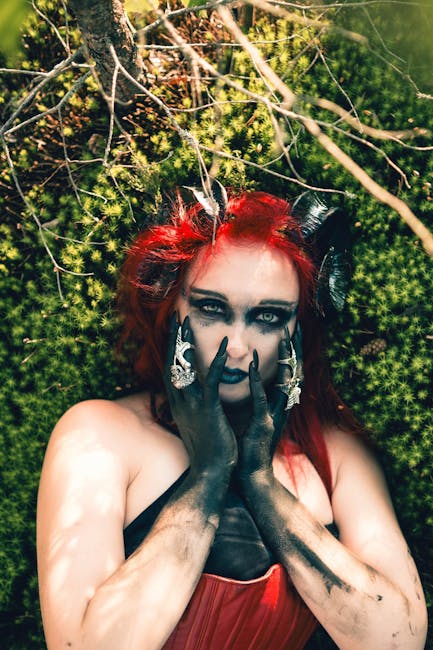 Enchanting forest portrait of a woman in fantasy costume with red hair and black makeup.