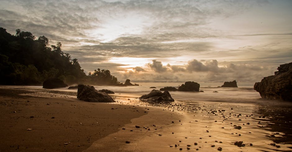 Scenic view of Nuquí beach, Chocó at sunset with rocky shoreline.
