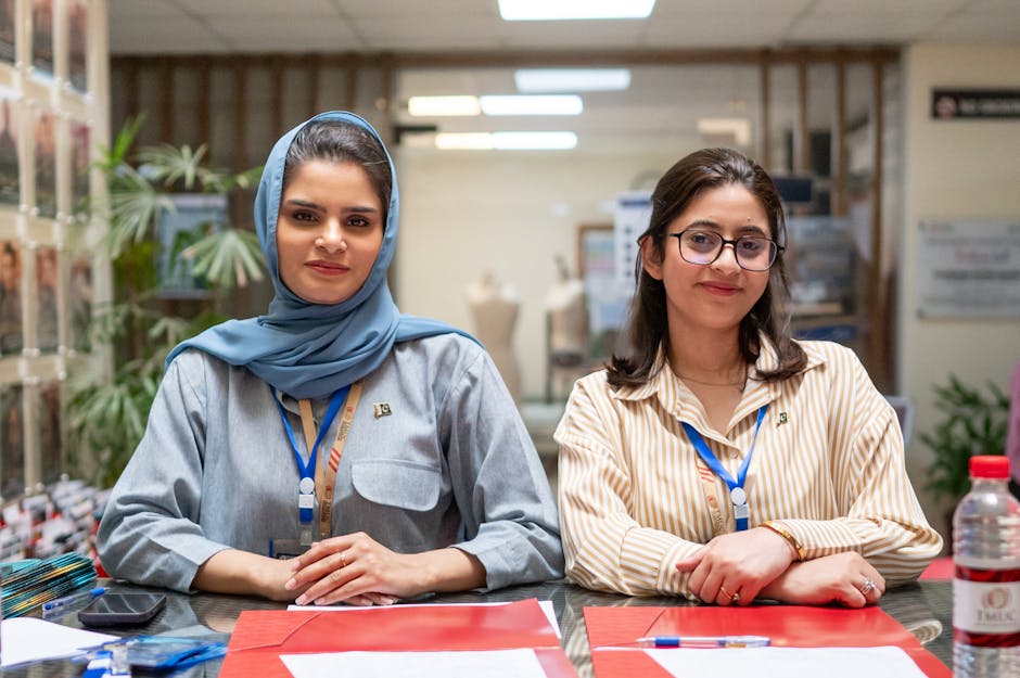 Two professional women colleagues at an office desk in Islamabad, showcasing diversity and teamwork.