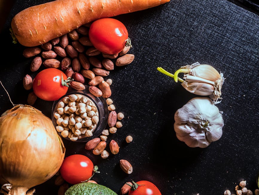 Top view of fresh vegetables and nuts arranged on a dark surface, showcasing raw ingredients.