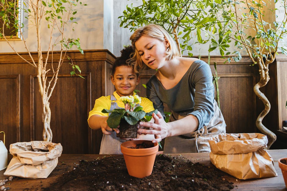 A woman and child enjoy planting a flower together indoors, surrounded by green plants.