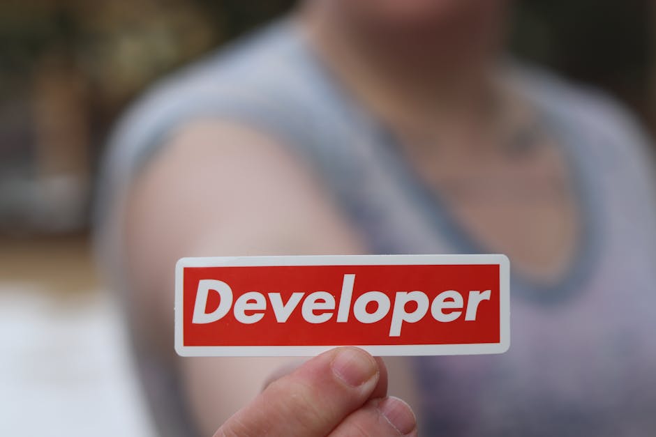 A close-up shot of a hand holding a red label with the word 'Developer' in focus.