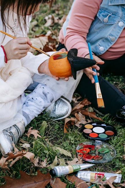 Two children creatively painting pumpkins outdoors for Halloween, showcasing fall activities.