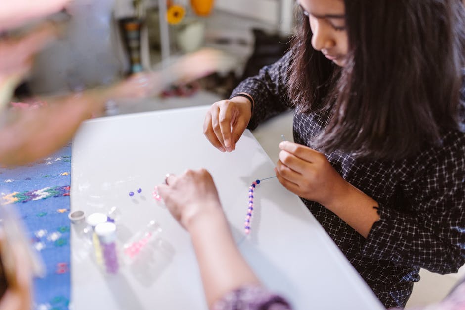 A child creating bead bracelets creatively indoors, focused on art and craft activity.