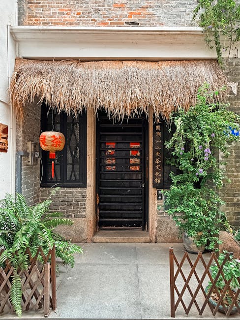 A rustic Chinese doorway with a straw roof and red lanterns, showcasing traditional architecture.