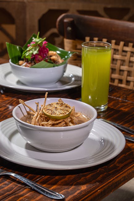 Aromatic Asian noodle dish and vibrant green drink on rustic table.