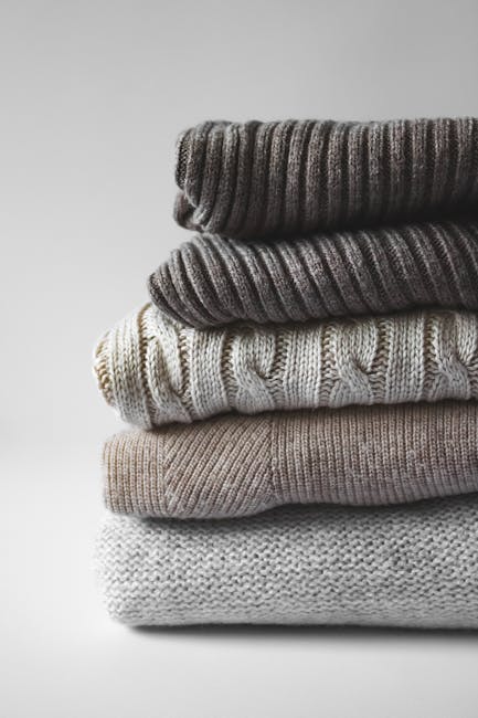 A neatly stacked pile of warm knitted sweaters, perfect for winter fashion.