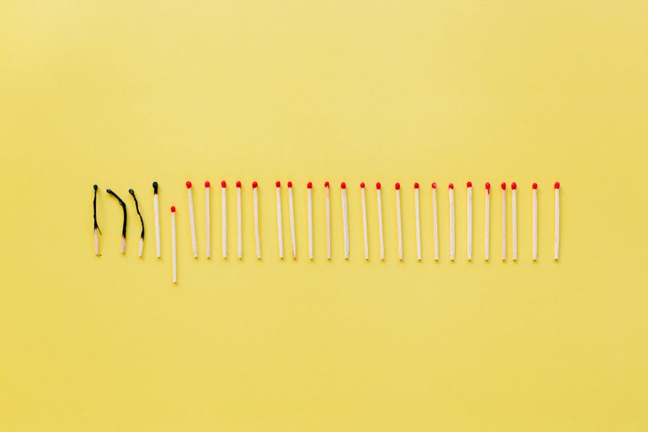A conceptual still life photo of burnt and unlit matches on a vibrant yellow background.