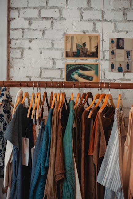 person arranging cotton clothes in wooden wardrobe