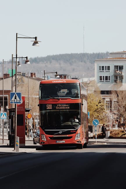 A red double-decker bus on a street in Jönköping, Sweden, showcasing Nordic architecture and urban life.