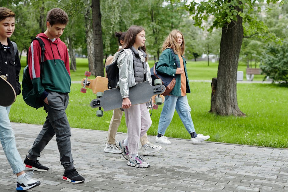Group of teenagers strolling in a park carrying skateboards on a sunny day.