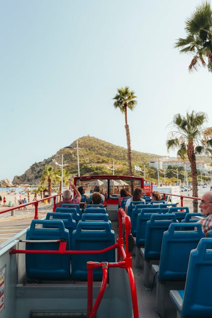 Experience stunning coastal views from an open-top tour bus on a sunny day.