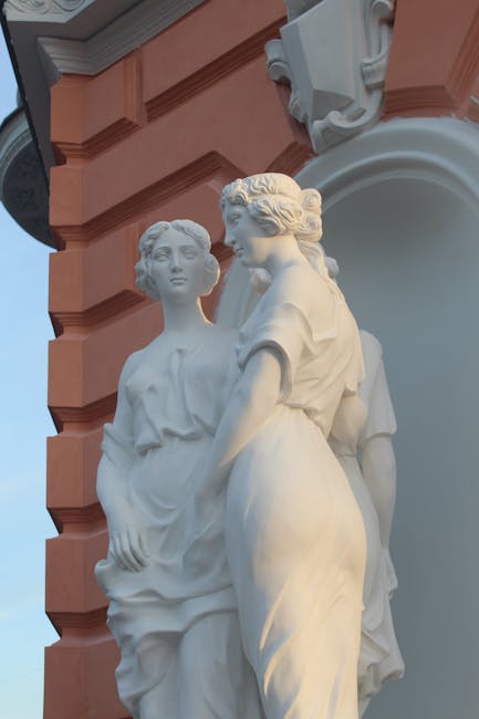 Close-up photo of a graceful white sculpture on a historic building exterior.