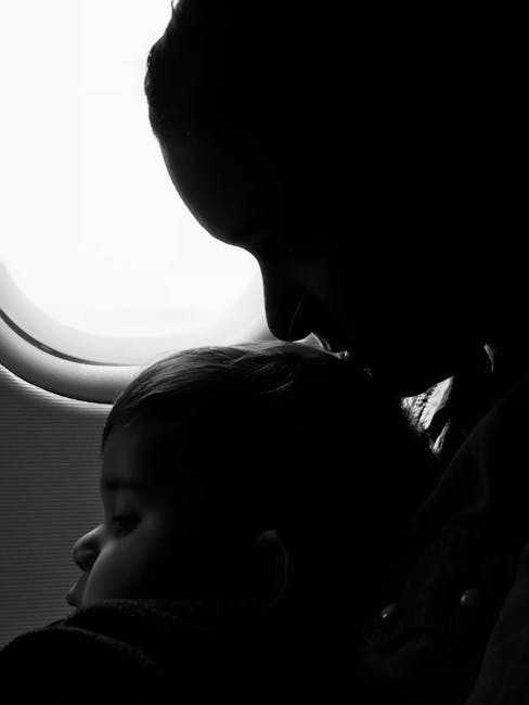 parent holding newborn airplane window seat