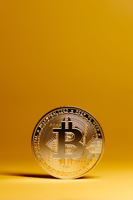A golden Bitcoin coin stands out against a vivid yellow background, representing digital currency and financial technology.