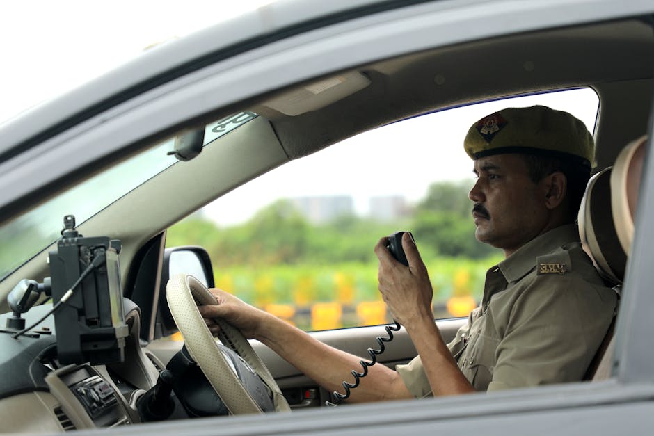 Police officer in uniform using a radio while seated in a vehicle, focused and attentive.