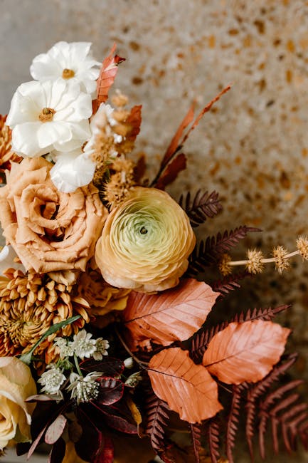 From above of bunch of delicate flowers consisting of ranunculus and rose with leaves and branches for decor